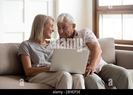 Happy older wife and husband using laptop together, having fun Stock Photo