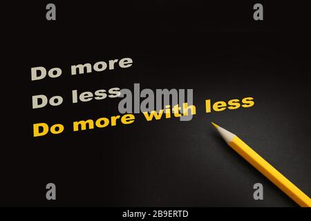 Do More With Less with yellow pencil on textured black paper. Lifestyle concept Stock Photo