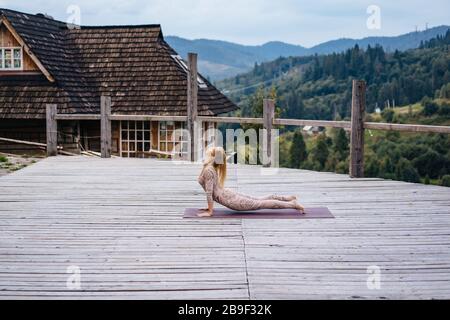 A woman practices yoga at the morning in a terrace on a fresh air.