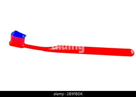 Blue toothpaste on the red toothbrush isolated on white background. Dental care concept Stock Photo