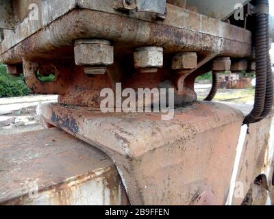 Old steel bolts and rusty nuts on a support beam plate. Structural detail of the base of a gantry crane support. Focus in the foreground. Industrial b Stock Photo