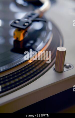 artistic dramatic shallow depth of field close up of record player with stylus needle on turntable with vinyl record on deck spinning with motion blur Stock Photo