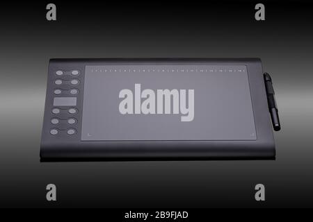 Digital graphic tablet with pen for illustrators and designers on a black background. Modern black graphic tablet for drawing closeup Stock Photo