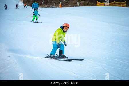 Young boy learning to ski. Although he has dirty clothes after he fell into mud, he still has smile on his face. Stock Photo