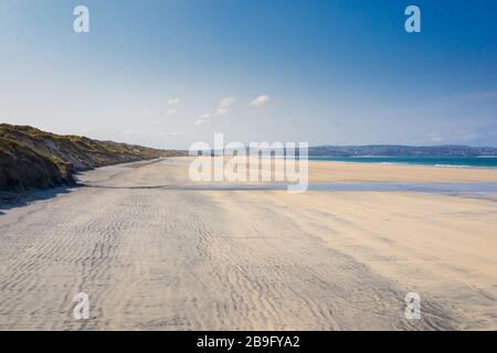 aerial photo of an empty Gwithian beach with waves breaking and sand dunes on a blue sky day with st ives in the background Stock Photo