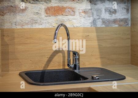 Modern contemporary loft interior of kitchen. Brick wall. CLose-up of black sink. Stock Photo