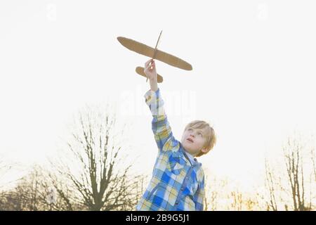 Boy playing with cardboard airplane in park Stock Photo