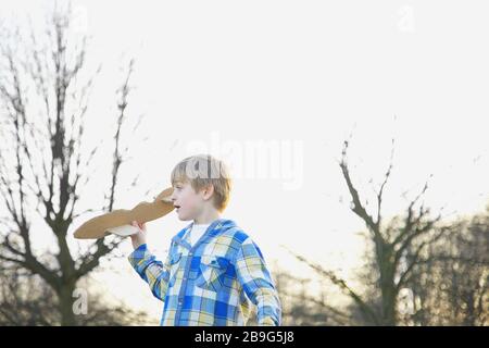 Boy playing with cardboard airplane in park Stock Photo
