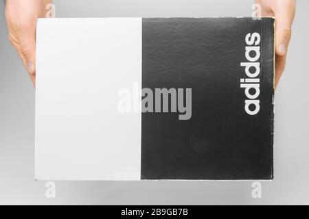 Close up mans hands holding a Adidas box on a white background. Man holds black and white box with Adidas logo, San Francisco, USA, March 2020 Stock Photo