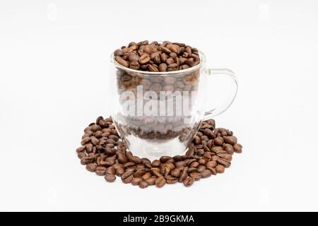 Glass thermos insulating cup transparent overfilled with roasted coffee beans on a white underground Stock Photo