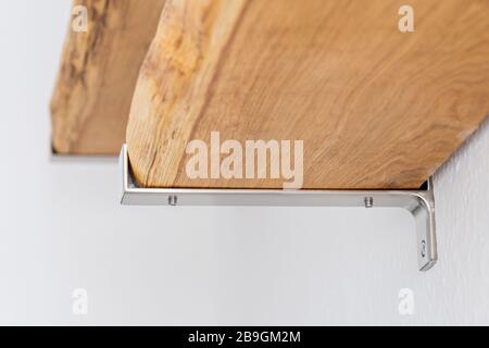 Shelves made by natural oak planks mounted with brushed steel attachment to the wall Stock Photo