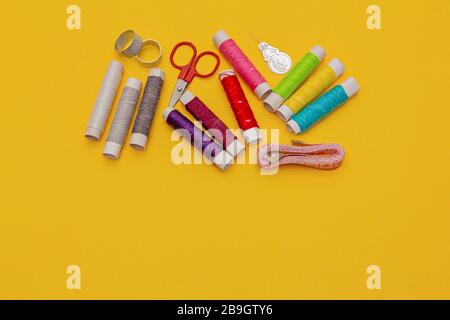 Thread, needles, scissors and meter on yellow background. tailoring set. sewing kit Stock Photo