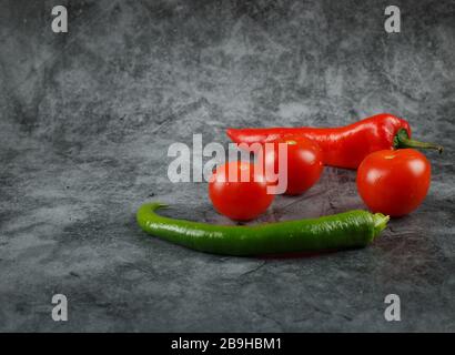 Tomatoes and green, red chilies on a marble. Stock Photo