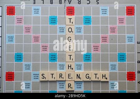 London, UK. 24th March, 2020. Scrabble Board with phrases and words related to Coronavirus help, positivity and support. STRENGTH TOGETHER Stock Photo