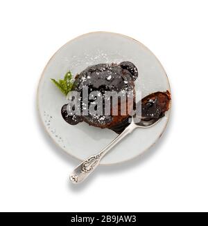 An individual chocolate sponge cake, with a sticky chocolate sauce, on a white plate with a spoon, isolated on white with a darop shadow. Stock Photo