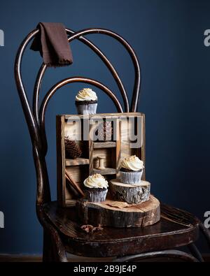 Chocolate cupcakes decorated with white butter cream and peanuts on vintage old chair at dark background. Free space for your text Stock Photo