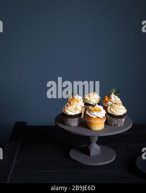 Assorted decorated chocolate and lemon cupcakes on dark background. Free space for your text Stock Photo