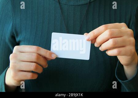 The girl holds a white rectangular card in her hands. Layout and mockup for design, place for text, copy space. Stock Photo