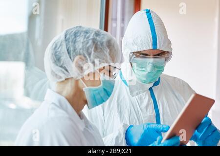 Doctors in clinic in intensive care unit look at patient's patient data on tablet computer Stock Photo