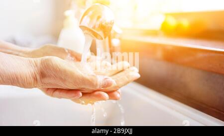 Elderly woman washing hands with liquid soap under water at the tap Stock Photo