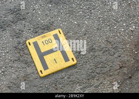 Traditional UK fire hydrant H sign / marker on ground separated from hydrant post. Metaphor fire safety, first responders, fire service, Fire Brigade. Stock Photo