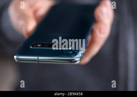 Man hold in hand modern smartphone with cracked corner Stock Photo