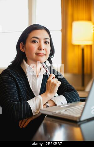 A young businesswoman using a laptop in her hotel room. Stock Photo
