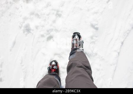Skier legs with black pants and his red ski boots walking on snow. Wintersport concept Stock Photo