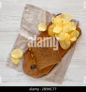 Homemade Peanut Butter Pickle Sandwich with Potato Chips on a rustic wooden board on a white wooden background, top view. Flat lay, overhead, from abo Stock Photo