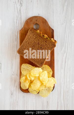 Homemade Peanut Butter Pickle Sandwich with Potato Chips on a rustic wooden board on a white wooden background, top view. Flat lay, overhead, from abo Stock Photo