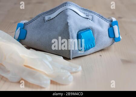 Respirator face mask with heavy-duty protective filter and latex gloves on a wooden light background. Madical face mask. Stock Photo