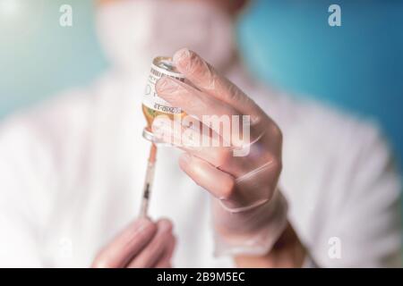 The scientist in a white medical apron and mask presents a new vaccine for the ncov2 virus. Vaccination against coronavirus. COVID-19 disease. Stock Photo