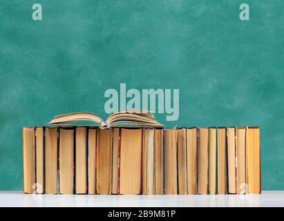 Back to school, pile of books with empty green school board background, education concept Stock Photo