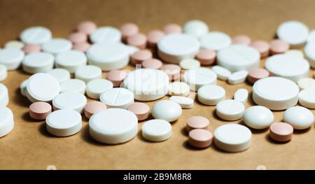 Heap of white pills, tablets, capsules on yellow orange background. Drug prescription for treatment medication health care concept wth copy space Stock Photo