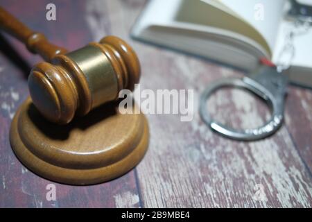 Close up of gavel, book and handcuff on table  Stock Photo