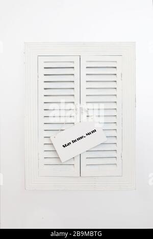 Name plate with words Stay home,Mom on wooden jalousie background. Concept of self quarantine at home as preventative measure against corona virus Cov Stock Photo