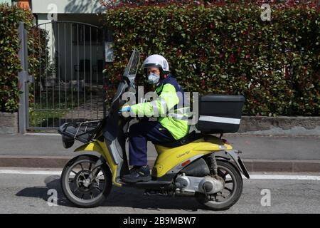 Pergine Valsugana, Italy. 24th Mar 2020. Most part of Europe is today on a sweeping confinement to try to slow down the spread of the Covid-19 Pandemic. A postman on his scooter wearing gloves and mask. (Photo by Pierre Teyssot/ESPA-Images) Credit: European Sports Photographic Agency/Alamy Live News Stock Photo