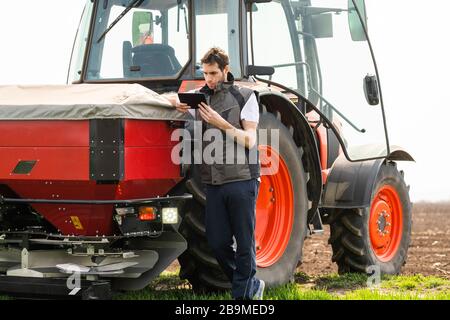 Male Agricultural Worker On tractor Using Digital Tablet. Stock Photo
