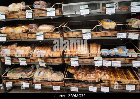 Different fresh bread on the shelves in bakery. Interior of a modern grocery store showcasing the bread aisle with a variety of prepackaged breads ava Stock Photo