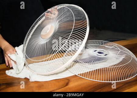 The housekeeper is installing the ceiling fan after being cleaned. Stock Photo