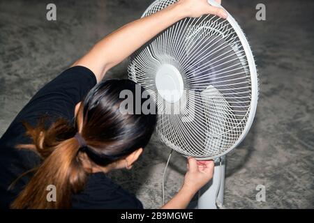 The housekeeper is installing the ceiling fan after being cleaned. Stock Photo