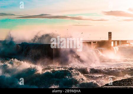 Waves crashing on a pier at sunset Stock Photo
