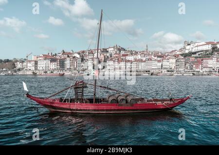 Wine barrels in a local traditional boat on the Douro River. Cityscape of the beautiful old town of Portugal - Porto, Nov.2019 Stock Photo