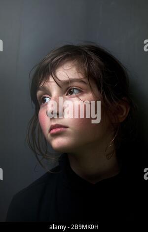 11 year-old boy looking out of a window during the coronavirus pandemic, Barcelona, Spain. Stock Photo