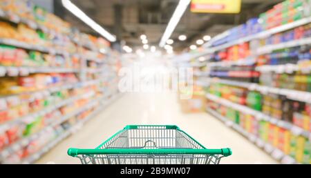 Supermarket aisle with empty green shopping cart Stock Photo