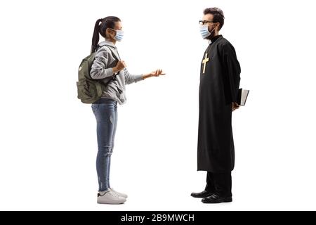 Full length profile shot of a female student talking to a priest, both wearing medical masks isolated on white background Stock Photo