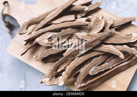 Slices of dried lingzhi mushroom, also called reishi or Ganoderma Lucidum, on a wooden board, gray background. Chinese traditional medicine product. Stock Photo