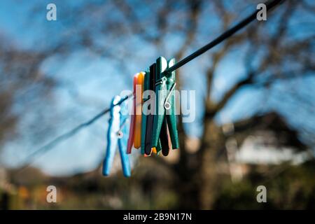 six clothespins hanging on a line with a blurry tree in the background Stock Photo
