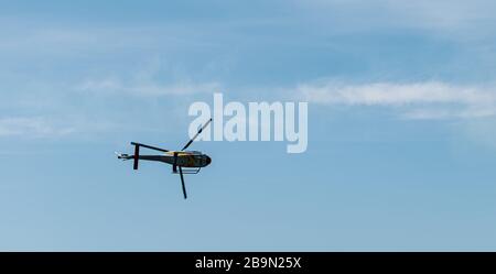 Military helicopter spinning with blue sky and clouds in the background Stock Photo