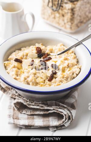 Bowl of oatmeal porridge with raisins on white table Stock Photo - Alamy